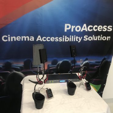Expocine - Imagem de uma sala de cinema com os equipamentos da Riole acessíveis para pessoas com deficiência visual e auditiva