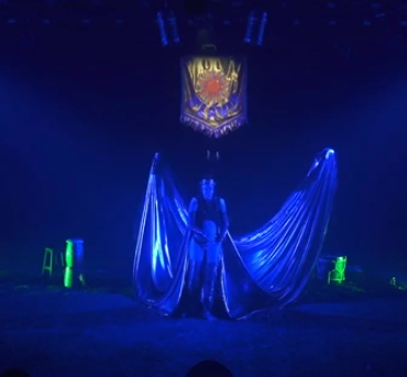 Com uma iluminação na cor azul, uma pessoa em pé com grandes asas.